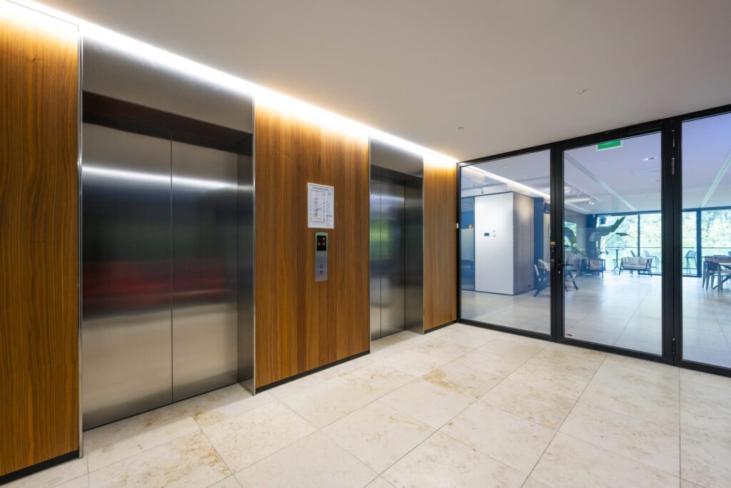 Modern elevator lobby with wood-paneled walls and glass doors at Gustav Mahlerlaan.